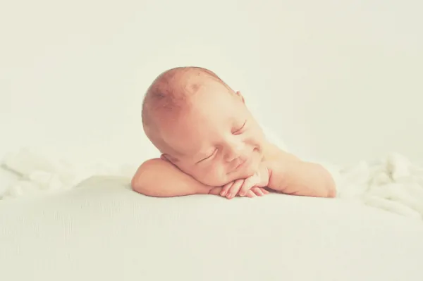 baby smiling as it sleeps on a white 